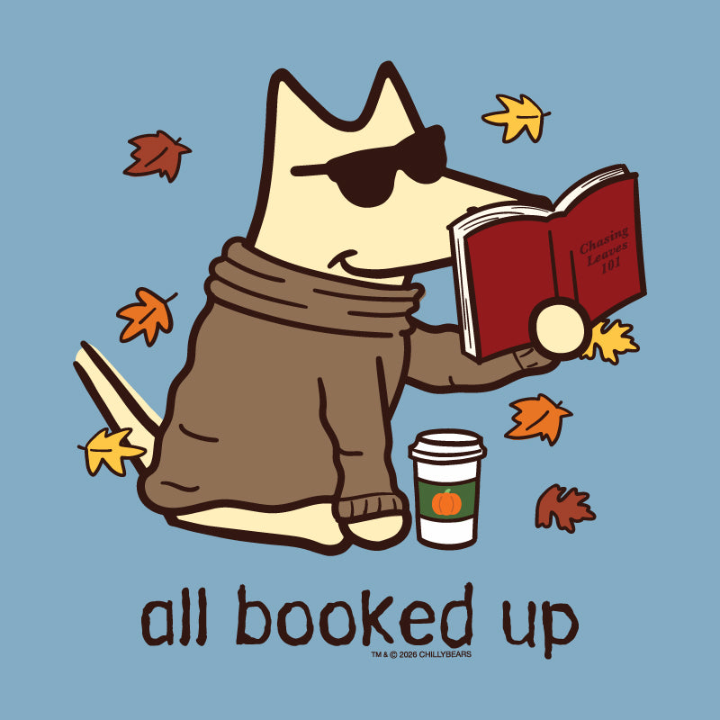 A stylized cartoon dog wearing sunglasses and a brown sweater sits on a light blue background, reading a red book with autumn leaves floating around it and the text 'all booked up' below.
