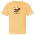 A pale yellow short-sleeve crewneck t-shirt featuring a cartoon graphic of a dog in a brown robe reading a red book, with the text 'all booked up' printed below.