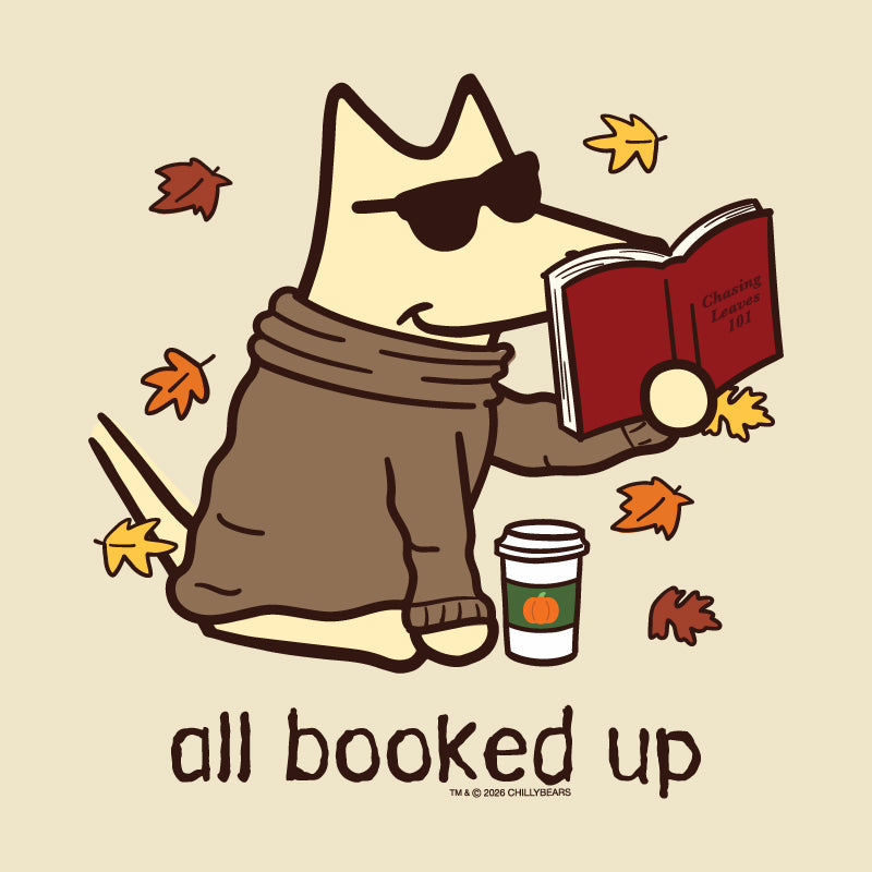 A stylized cartoon dog wearing dark sunglasses and a brown sweater sits reading a red book, surrounded by falling autumn leaves, with the text 'all booked up' below. A small coffee cup appears beside the dog.