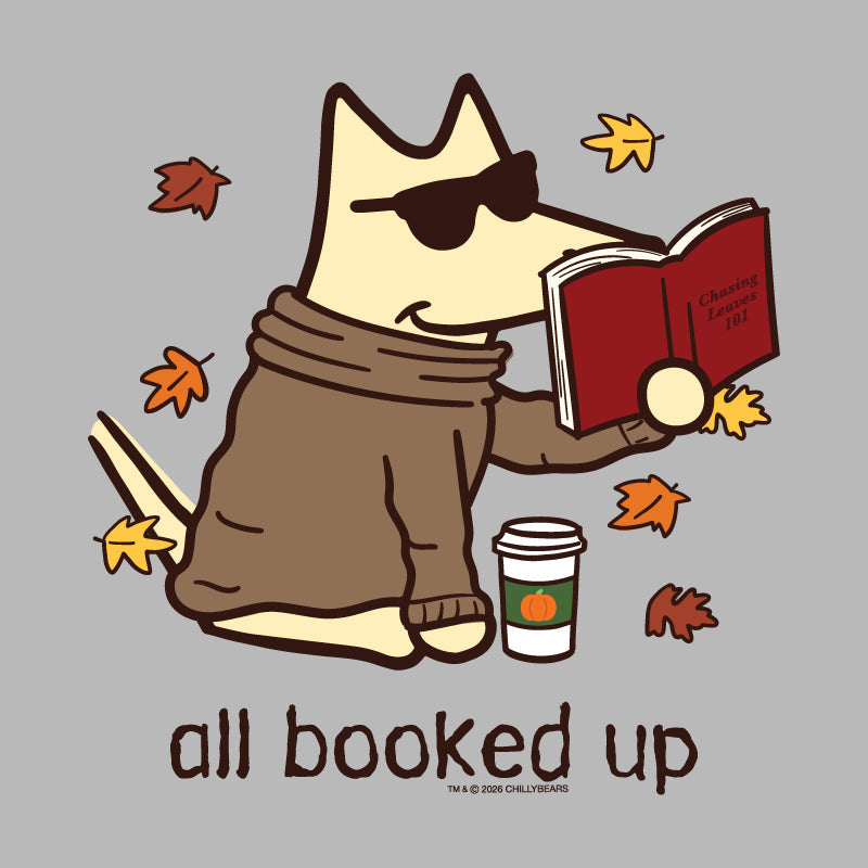 A cartoon dog wearing dark sunglasses and a brown sweater sits on a gray background, reading a red book with autumn leaves floating around it and the text 'all booked up' below.