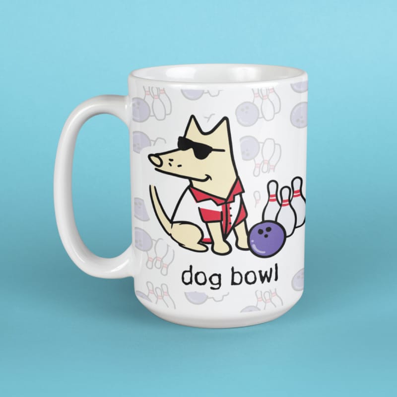 A white ceramic mug featuring a cartoon dog wearing sunglasses and a red-and-white striped shirt bowling with pins and a purple bowling ball, with the text 'dog bowl' below. The mug is set against a solid light blue background.