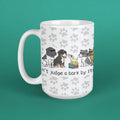 A white ceramic mug with a handle, featuring a printed design of various dog breeds sitting on books with the text 'Don't judge a bark by its.