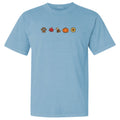 A light blue short-sleeve crewneck t-shirt featuring a horizontal row of five small autumn-themed icons on the chest: a paw print, a red maple leaf, a fox, a pumpkin, and a sunflower.