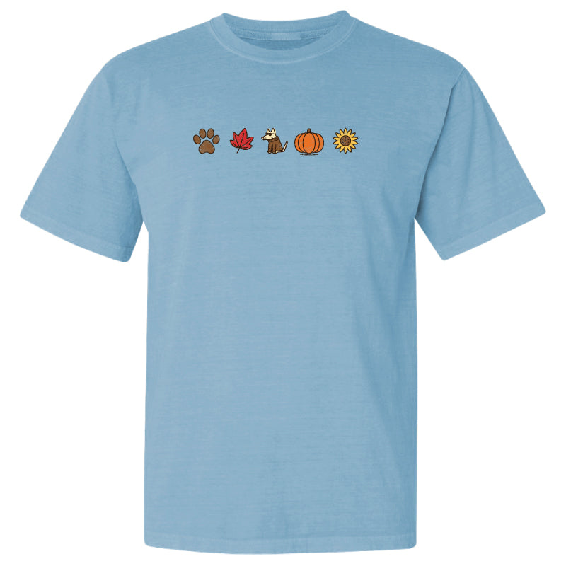 A light blue short-sleeve crewneck t-shirt featuring a horizontal row of five small autumn-themed icons on the chest: a paw print, a red maple leaf, a fox, a pumpkin, and a sunflower.