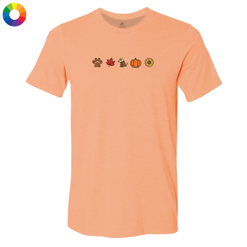 A peach-colored short-sleeve t-shirt with a row of small autumn-themed icons printed across the chest, including a paw print, maple leaf, dog, pumpkin, and sunflower. A circular multicolor color wheel icon is visible in the top-left corner.