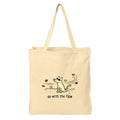 A natural beige canvas tote bag with two shoulder straps, featuring a minimalist black line art illustration of a dog surrounded by autumn leaves and the text 'go with the flow' printed on the front.