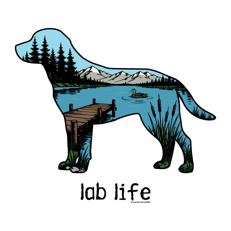 A die-cut sticker or graphic featuring a dog silhouette filled with a scenic landscape illustration of a lake, mountains, dock, trees, and a duck, with the text 'lab life' below on a white background.