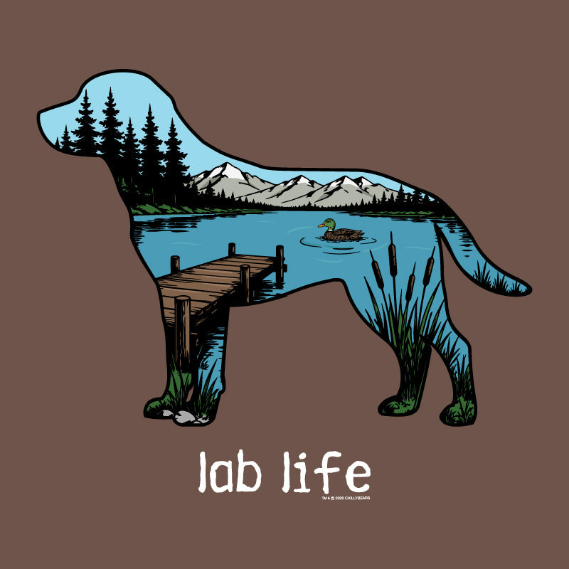 A brown graphic design featuring a dog silhouette filled with a scenic landscape illustration of a lake, mountains, dock, trees, and a duck. Below the dog, the text reads 'lab life' in white.