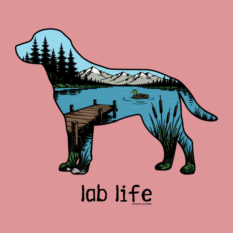 A pink square graphic featuring a stylized dog silhouette filled with a scenic lake landscape, including mountains, pine trees, a dock, reeds, and a duck. Below the dog, the text reads 'lab life' in black.