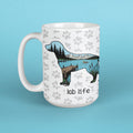 A white ceramic coffee mug with a handle, decorated with a gray paw print pattern and a graphic silhouette of a Labrador retriever filled with a lake, mountains, and pine tree scene. The text 'lab life' is printed below the graphic.