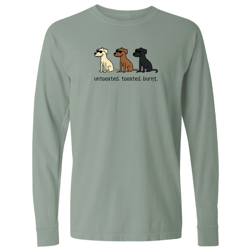 A sage green long-sleeve t-shirt with a graphic of three dogs (white, brown, and black) and the text 'untasted. toasted.