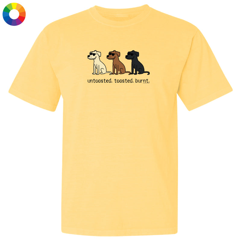 A pale yellow short-sleeve t-shirt with a graphic of three dogs in white, brown, and black, with the text 'untoasted. toasted.