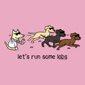 A pink graphic print featuring a cartoon dog in a white lab coat running behind three other dogs wearing sunglasses, with the text 'let's run some labs' below. Small text at the bottom right reads 'WE'VE BOTH OWNED DOGNAME'.