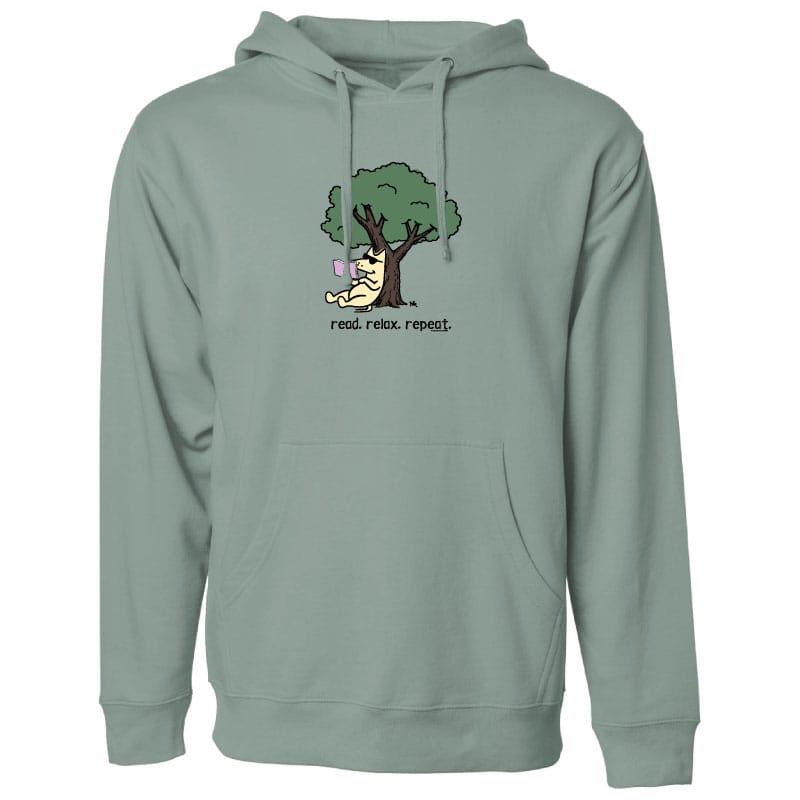 A sage green pullover hoodie with a front kangaroo pocket and drawstrings, featuring a cartoon graphic of a dog under a tree with the text 'read, relax, repeat.' on the chest.
