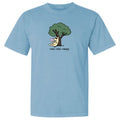 A light blue short-sleeve crewneck t-shirt featuring a cartoon graphic of a dog sitting under a tree reading a book, with the text 'read. relax.