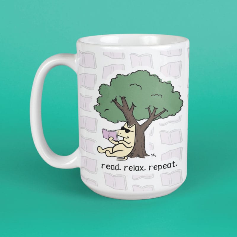 A white ceramic mug with a cartoon illustration of a dog reading under a tree, with the text 'read. relax.