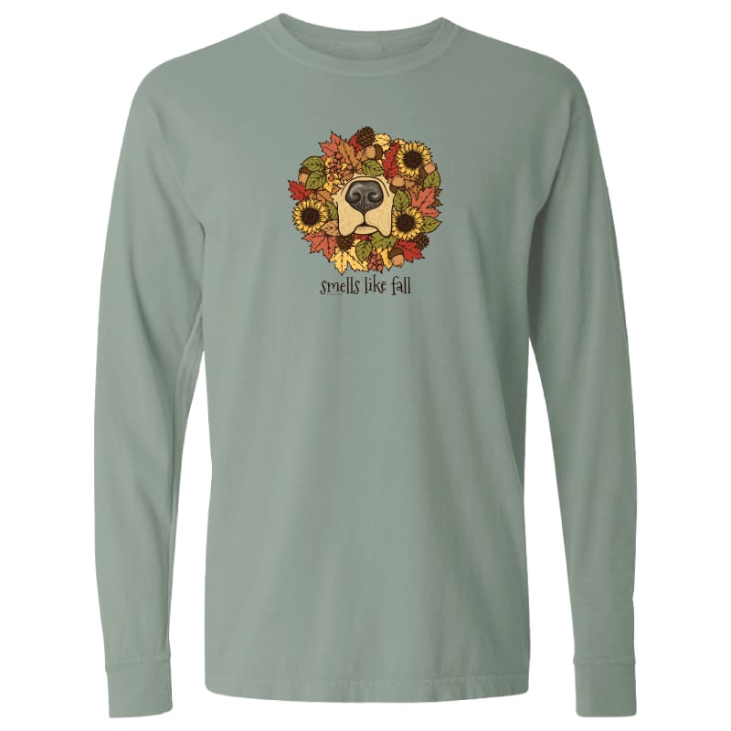 A sage green long-sleeve t-shirt with a graphic of a dog's face surrounded by autumn leaves and sunflowers, with the text 'smells like fall' printed below the graphic.