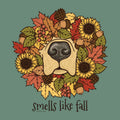 A circular autumn wreath illustration featuring a dog nose in the center, surrounded by sunflowers, fall leaves, acorns, pinecones, and berries, with the text 'smells like fall' below on a muted green background.