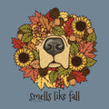A circular autumn wreath illustration featuring a dog nose at the center, surrounded by sunflowers, fall leaves, acorns, pinecones, and berries, with the text 'smells like fall' below on a muted blue-gray background.
