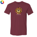 A maroon short-sleeve crewneck t-shirt featuring a graphic of a dog's face surrounded by autumn leaves and sunflowers, with the text 'smells like fall' printed below. A small multicolor color wheel icon is visible in the top-left corner.