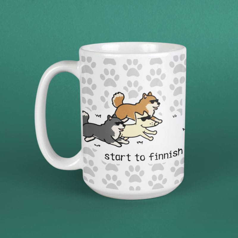 White mug with cartoon dogs and 'start to finnish' text on a green background