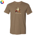 A heather brown short-sleeve t-shirt with a cartoon graphic of a dog wearing a plaid blanket and holding a basket of red apples, with the text 'the dog days of fall' printed below. A small circular color wheel icon is in the top-left corner.