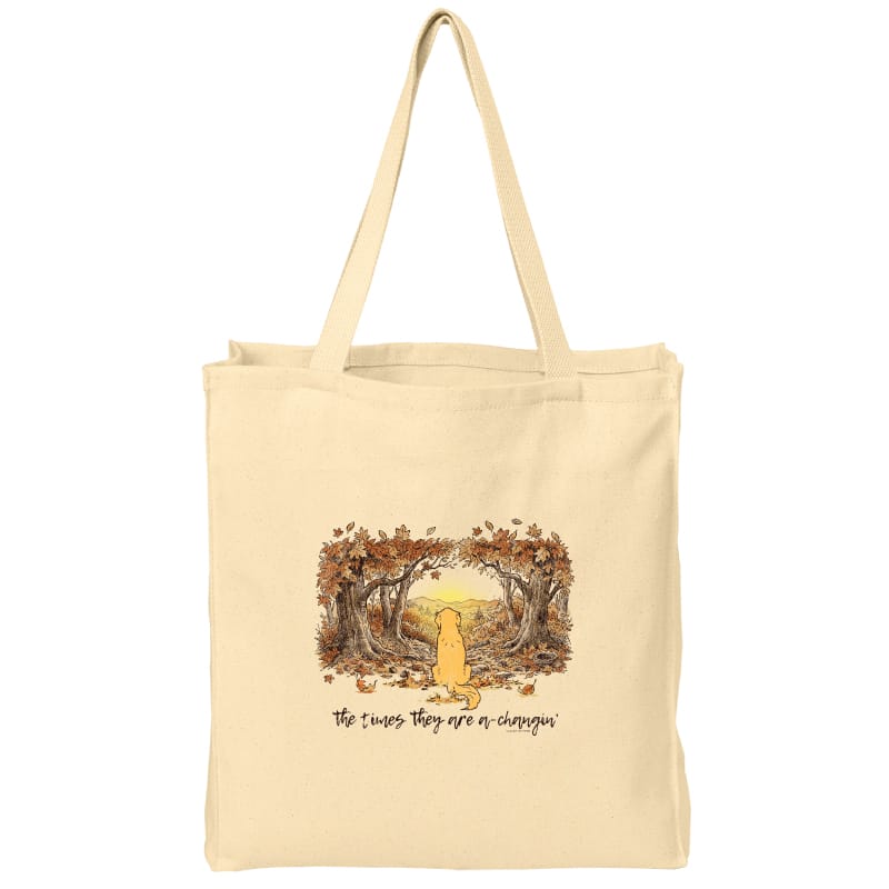 A natural canvas tote bag with a printed illustration of a yellow dog standing under an autumn tree arch, with the text 'The dogs they are a chihuahua' below the artwork, shown on a plain white background.