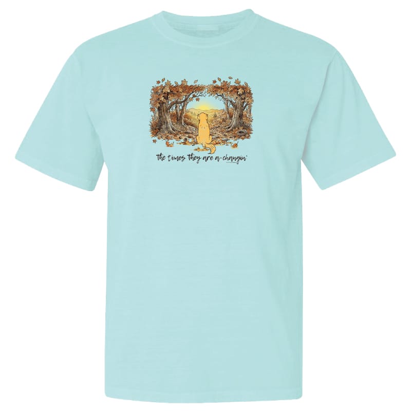 A light aqua blue short-sleeve crewneck t-shirt featuring a central graphic of a yellow dog sitting in a forest of falling leaves with the text 'The Cactus They Eat or Choke' printed below.