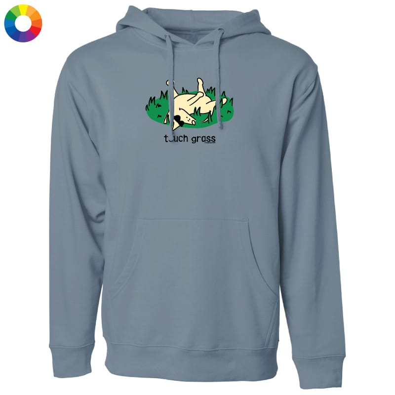 A dusty blue-gray pullover hoodie with a graphic on the chest showing a hand making a shaka sign in grass with the text 'touch grass'. The hoodie is displayed on a clean white background with a small multicolor color wheel icon in the top-left corner.